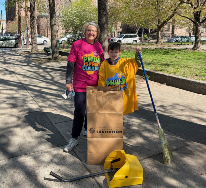 A photo of our an adult and a child helping clean Campbell Square for the Philly Spring Clean Up Day.